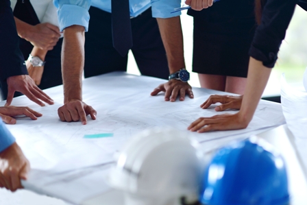 business people group on meeting and presentation in bright modern office with construction engineer architect and worker looking building model and blueprint planbleprint plans